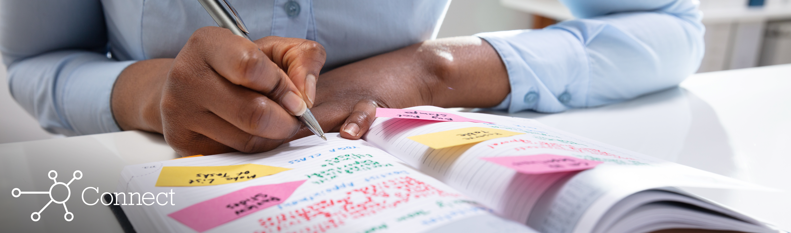 A woman writing out a social media content schedule in a daily planner notebook
