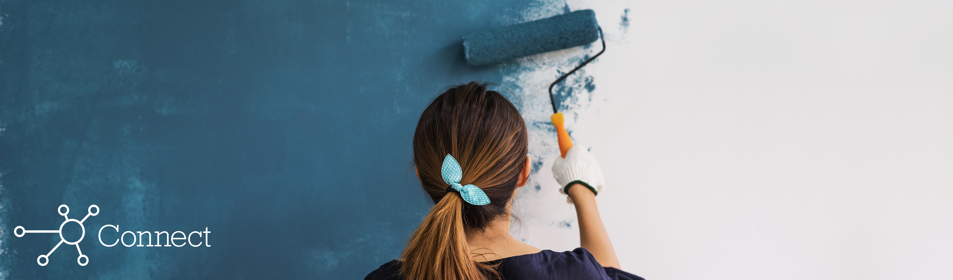 A woman painting the walls of her pharmacy blue using a paint roller